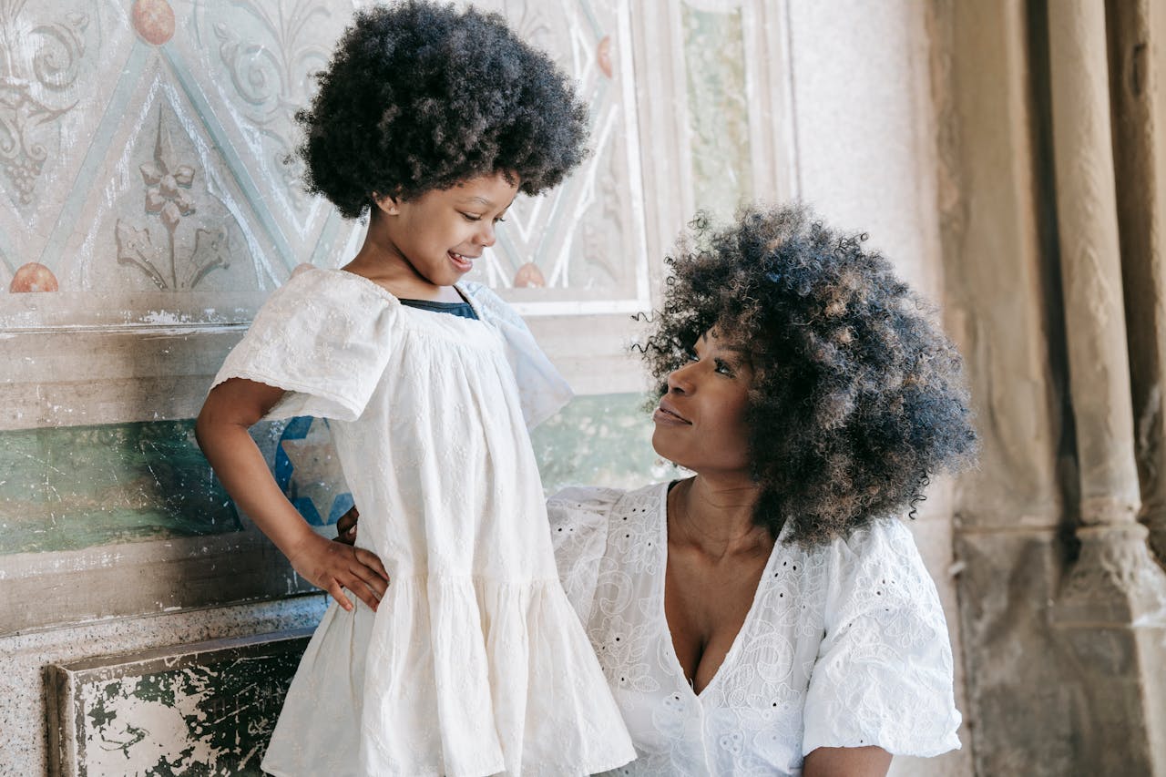 A joyful mother and daughter sharing a moment in matching stylish outfits indoors.