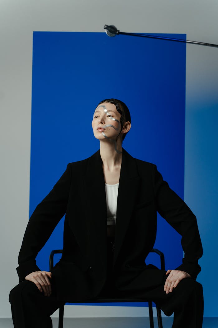 Model with artistic makeup posing in a studio with blue background. Modern and conceptual.